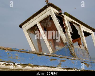 La maison pilote d'un vieux bateau de pêche épaté sur la plage de Dungeness sur la côte sud de l'Angleterre. Ce bateau, abandonné et haut et sec, ne naviguera plus. Banque D'Images