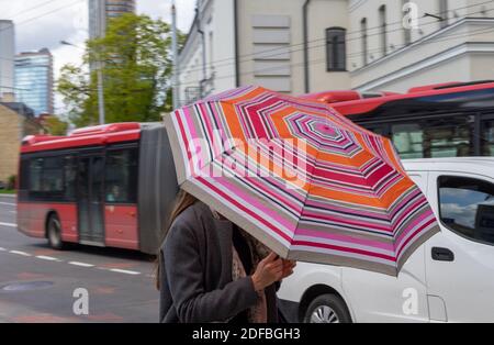 Jeune fille sous des parasols de couleurs mélangées dans une rue animée Banque D'Images