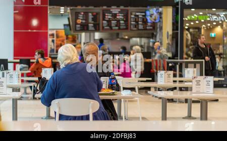 Un couple de personnes âgées ordinaires déjeunant à la cafétéria. Vue sur la rue, photo de voyage. Banque D'Images