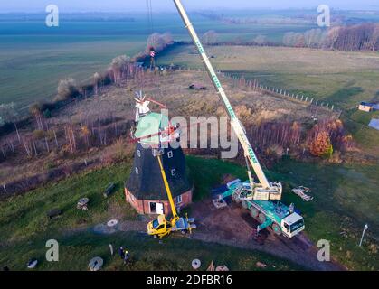 Cuisinière, Allemagne. 14 septembre 2017. Une grue est utilisée pour enlever le chapeau de moulin du moulin à vent, qui pèse environ 17 tonnes, pour les travaux de rénovation. Le moulin à vent néerlandais, construit en 1889, doit être fixé avant l'hiver en raison des dommages à la couronne à rouleaux et est doté d'un toit d'urgence temporaire. Au cours des prochaines années, l'association des moulins et la municipalité de Salzhaff veulent reconstruire l'usine pour qu'elle soit à nouveau fonctionnelle. (Tourné avec un drone) Credit: Jens Büttner/dpa-Zentralbild/ZB/dpa/Alay Live News Banque D'Images