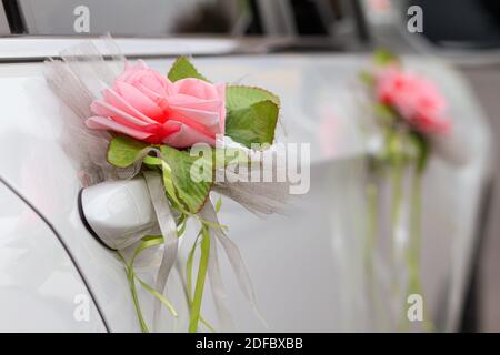 Belle voiture blanche décorée de boutonnière de fleur rose pour le mariée et marié le jour du mariage Banque D'Images