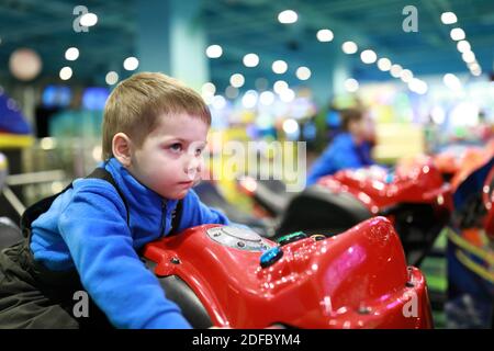 Enfant jouant au simulateur de moto dans le parc d'attractions Banque D'Images