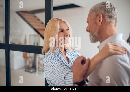 Femme blonde embrassant son petit ami et souriant avec joie Banque D'Images
