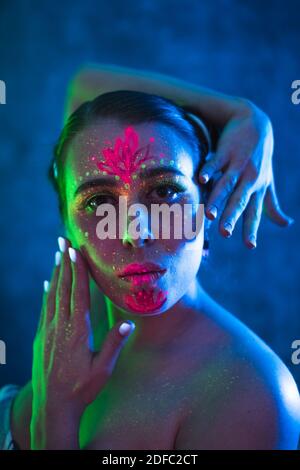 Portrait de femme peinte en poudre fluorescente et peinture. Prise de vue colorée, intéressante et inhabituelle. Banque D'Images