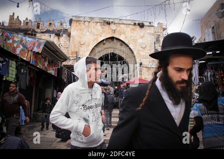 Israël, Jérusalem, l'homme arabe et le handim ultra orthodoxe juif traditionnel homme marcher togethter près de la porte de Damas Banque D'Images