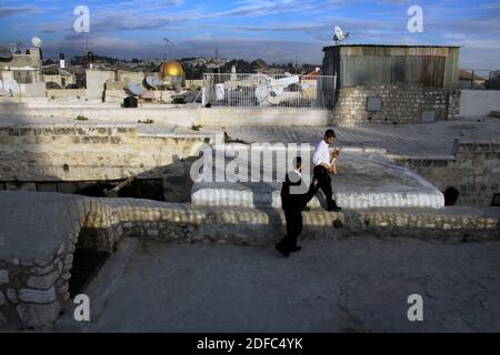 Israël, mosquée Al-Aqsa au loin, deux hommes juifs marchent au coucher du soleil sur les toits de la vieille ville de Jérusalem Banque D'Images