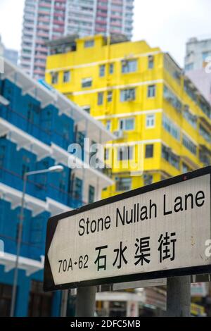 Hong Kong, panneau en pierre de Nullah Lane avec des maisons jaunes et bleues à l'arrière des bâtiments Banque D'Images