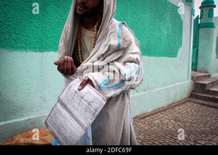 Ethiopie, un mendiant montre un livre avec des écrits arabes à l'intérieur en face de la mosquée dans la vieille ville de Harar Banque D'Images