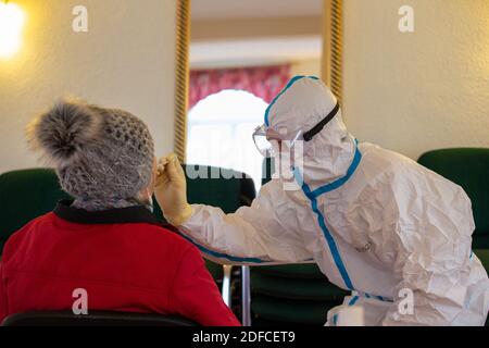 Rathmannsdorf, Allemagne. 04e décembre 2020. Un homme en costume de protection prend un échantillon de gorge de celui d'une dame plus âgée. Les habitants de la communauté de Rathmannsdorf, dans le district administratif de la Suisse saxonne-Ore orientale, sont soumis à des tests de dépistage du virus SRAS-COV-2 (coronavirus). Le ministère des Affaires sociales et de la cohésion sociale (SMS) de l'État de Saxe souhaite utiliser cette campagne pour acquérir des connaissances sur la pénétration du virus dans cinq districts sélectionnés. Credit: Daniel Schäfer/dpa-Zentralbild/dpa/Alay Live News Banque D'Images