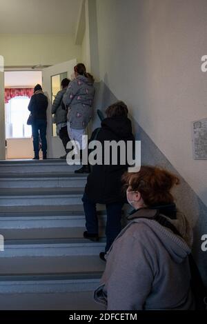 Rathmannsdorf, Allemagne. 04e décembre 2020. Les gens qui veulent être testés attendent dans l'escalier du centre communautaire. Les habitants de la communauté de Rathmannsdorf, dans le district administratif de la Suisse saxonne-est d'Erzgebirge, sont soumis à des tests de dépistage du virus SRAS-COV-2 (coronavirus). Le ministère des Affaires sociales et de la cohésion sociale (SMS) de l'État de Saxe souhaite utiliser cette campagne pour acquérir des connaissances sur la pénétration du virus dans cinq districts sélectionnés. Credit: Daniel Schäfer/dpa-Zentralbild/dpa/Alay Live News Banque D'Images