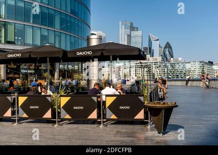 Les gens qui font leurs repas à l'extérieur au restaurant Gaucho (Tower Bridge) avec la City of London dans le Backround, London Bridge City Area, Londres, Royaume-Uni. Banque D'Images