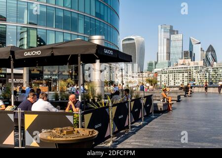 Les gens qui font leurs repas à l'extérieur au restaurant Gaucho (Tower Bridge) avec la City of London dans le Backround, London Bridge City Area, Londres, Royaume-Uni. Banque D'Images