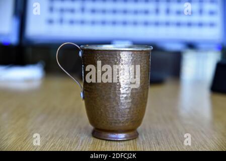 Un gros plan d'une tasse de cuivre remplie d'eau sur une surface en bois Banque D'Images