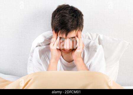 Un jeune homme ressent des maux de tête dans le lit à la maison Banque D'Images
