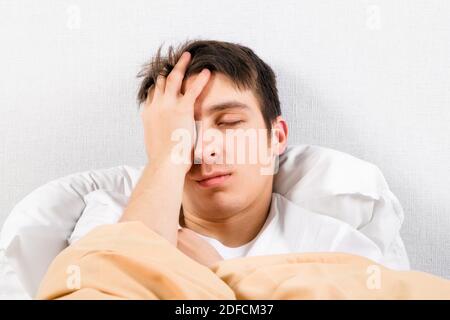 Un jeune homme ressent des maux de tête dans le lit à la maison Banque D'Images