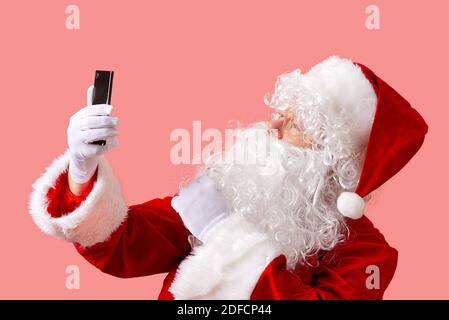 père noël avec téléphone portable isolé sur fond rose Banque D'Images