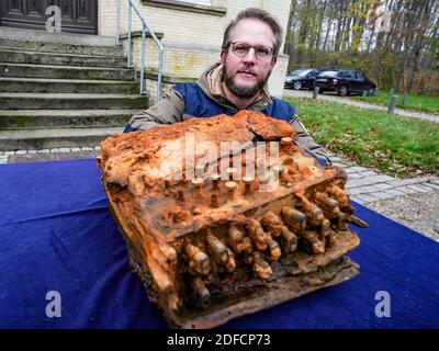 Schleswig, Allemagne. 04e décembre 2020. Florian Huber, plongeur de recherche, s'agenouille devant le bureau archéologique du Schleswig-Holstein lors de la remise de la machine de chiffrement Enigma, qu'il a trouvée dans la mer Baltique, à côté de la machine. Credit: Axel Heimken/dpa/Alay Live News Banque D'Images