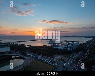 Coucher de soleil à la baie de Manille avec Roxas Boulevard et Manila Yacht Club en premier plan. Banque D'Images