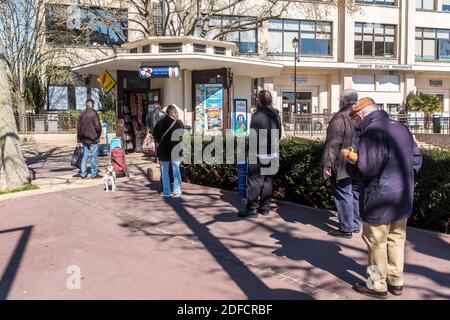 LIGNE D'ATTENTE DEVANT UN KIOSQUE DE JOURNAUX, PERSONNES RESPECTANT LES DISTANCES DE SÉCURITÉ PENDANT LE CONFINEMENT PANDÉMIQUE COVID-19, PARIS, ILE DE FRANCE Banque D'Images