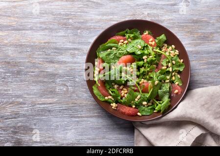 Salade fraîche d'arugula avec pamplemousse et pignons de pin sur fond de bois. Des aliments sains et délicieux Banque D'Images