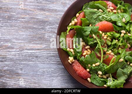 Salade fraîche d'arugula avec pamplemousse et pignons sur fond de bois, foyer sélectif, espace libre. Des aliments sains et délicieux Banque D'Images