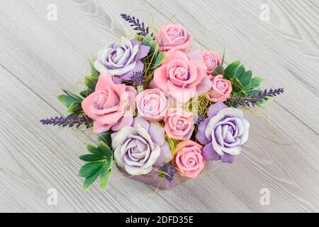 Savon sous forme de différentes fleurs colorées sur fond de bois gris. Vue de dessus. Banque D'Images