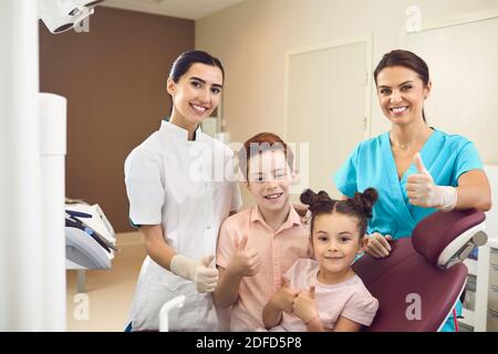 Clinique dentaire. Dentiste souriant, infirmière et enfants, garçon et fille regardant la caméra pendant la visite Banque D'Images