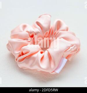 Soie rose Scrunchy isolé sur fond blanc. Outil de coiffure de la bande de cheveux élastique colorée, Bobble Scrunchie Hairband. Image carrée Banque D'Images