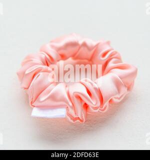 Soie rose Scrunchy isolé sur fond blanc. Outil de coiffure de la bande de cheveux élastique colorée, Bobble Scrunchie Hairband. Image carrée Banque D'Images
