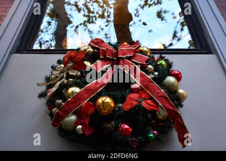 Couronne de Noël rétro en branches de sapin vert et boules dorées avec noeud en ruban rouge. Décoration de bienvenue sous la fenêtre Banque D'Images