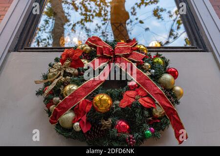 Couronne de Noël traditionnelle faite de branches de sapin vert et de boules dorées avec noeud en ruban rouge. Décoration de bienvenue de vacances Banque D'Images