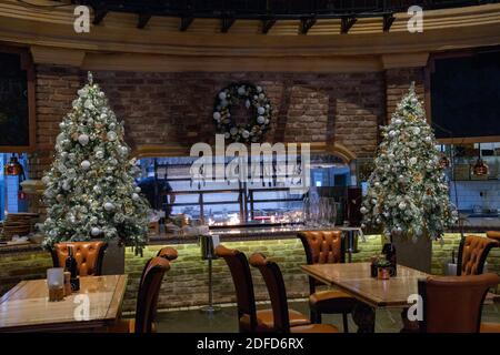 Arbres de Noël artificiels étincelants avec guirlande argentée et décorations de Noël dorées blanches. Fête du nouvel an au restaurant Banque D'Images
