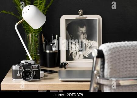 Un espace de bureau organisé avec une caméra d'époque. La décoration crème, noire et argentée offre une atmosphère détendue pour un travail productif à domicile. Banque D'Images