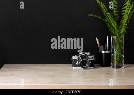 Un espace de bureau organisé avec une caméra d'époque. La décoration crème, noire et argentée offre une atmosphère détendue pour un travail productif à domicile. Banque D'Images