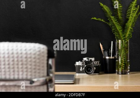 Un espace de bureau organisé avec une caméra d'époque. La décoration crème, noire et argentée offre une atmosphère détendue pour un travail productif à domicile. Banque D'Images