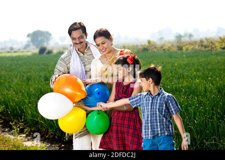 Famille indienne heureuse de fermiers avec des ballons dans le champ agricole Banque D'Images