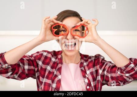 Jeune femme au foyer avec une coiffure de bob jouant avec des tranches de papier doux coupé de nourriture tout en cuisinant dans la cuisine. Une alimentation saine à la maison. Une alimentation saine Banque D'Images