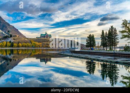 Parc national des Lacs-Waterton bord du lac en automne saison des feuillages matin. Ciel bleu, nuages colorés réfléchissent sur la surface du lac comme un miroir au lever du soleil. Banque D'Images