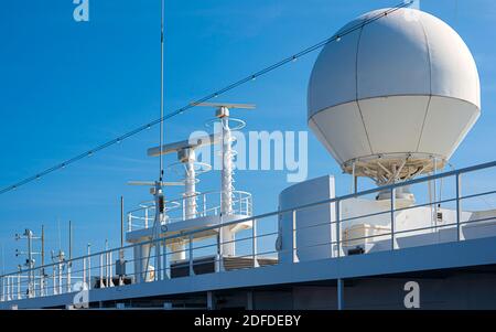 Antenne satellite de couleur blanche de cargo, un navire et des chaises longues sur le pont du navire de croisière Banque D'Images