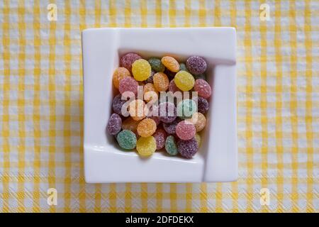 Rowntrees Jelly Tots sucreries dans un bol sur jaune et blanc serviettes de table à carreaux Banque D'Images