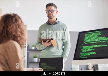 Homme d'affaires mature avec tablette pc discutant de la présentation en ligne avec elle collègue au bureau Banque D'Images