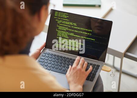Vue arrière du programmateur de logiciel femelle qui tape les codes sur l'ordinateur portable utilisation d'un nouveau logiciel Banque D'Images