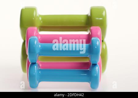 Forme ajustée et concept sport. Haltères en plastique bleu, rose et vert sur fond blanc. Le régime de santé et les symboles de condition physique. Cloches de différentes tailles mises en forme, gros plan Banque D'Images