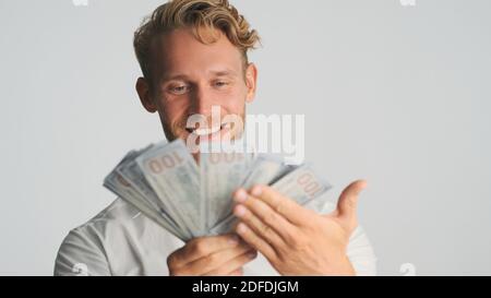 Portrait d'un homme d'affaires barbu qui semble heureux de montrer son bonheur argent sur l'appareil photo et sourire sur fond blanc Banque D'Images