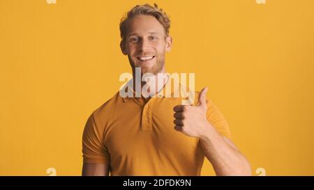 Beau barbu montrant le pouce vers le haut et souriant sur l'appareil photo sur fond bleu. Comme un geste Banque D'Images