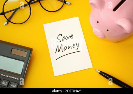 Économisez de l'argent. Banque de porc et calculatrice sur fond jaune. Banque D'Images
