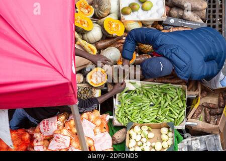 Vue d'en haut de personnes mettant des légumes dans un sac dans une rue à Brixton Market, Electric Avenue, Brixton, Londres Banque D'Images