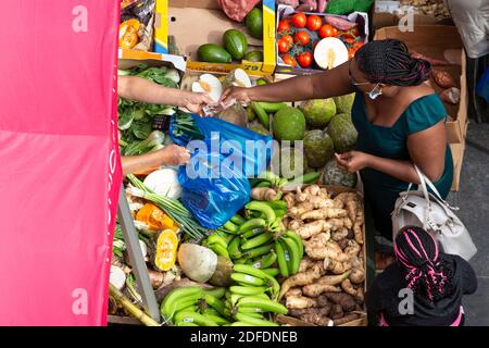 Une femme qui paie des produits dans un arrêt de rue à Brixton Market, Electric Avenue, Brixton, Londres Banque D'Images