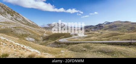 Paysage panoramique avec une route qui descend sur des pentes stériles en hauteur plate, prise du côté ouest en lumière vive à Campo Imperatore, l'Aquila, AB Banque D'Images