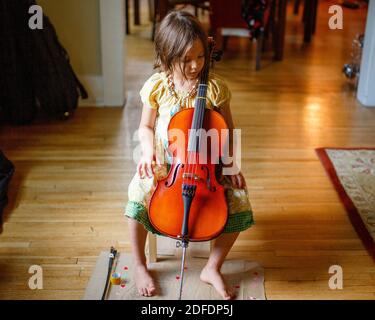 au-dessus de la vue de l'enfant pieds nus mignon dans la fenêtre de la lumière tenant un petit violoncelle Banque D'Images